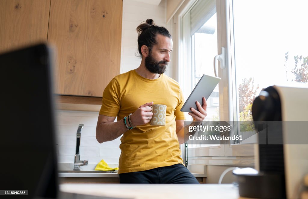 Mature man with digital tablet in kitchen at home