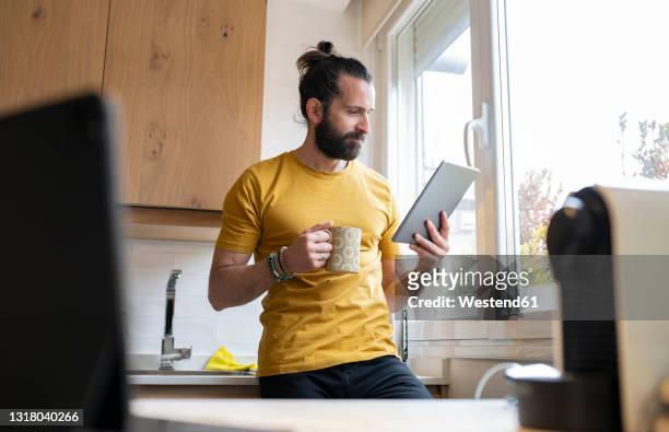 mature man with digital tablet in kitchen at home - differential focus stock pictures, royalty-free photos & images