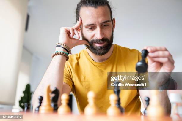 handsome man playing chess at home - chess stock pictures, royalty-free photos & images