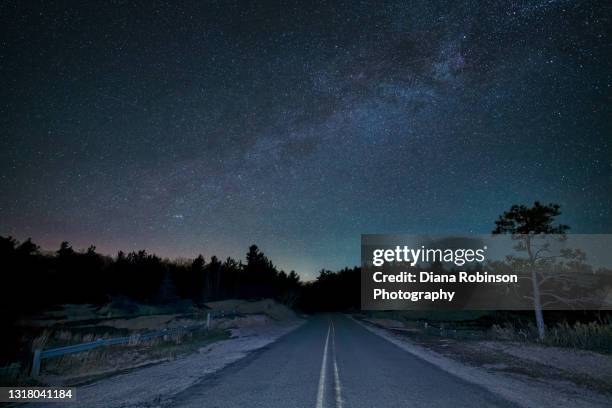 northern lights and milky way over the road through the sand dunes at sturgeon bay, wilderness state park, northern michigan - northern lights michigan bildbanksfoton och bilder