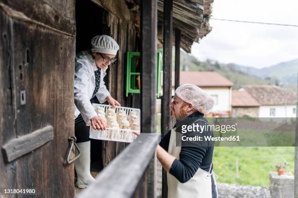 smiling owner giving cheese tray to colleague at doorway - アルチザンフード ストックフォトと画像