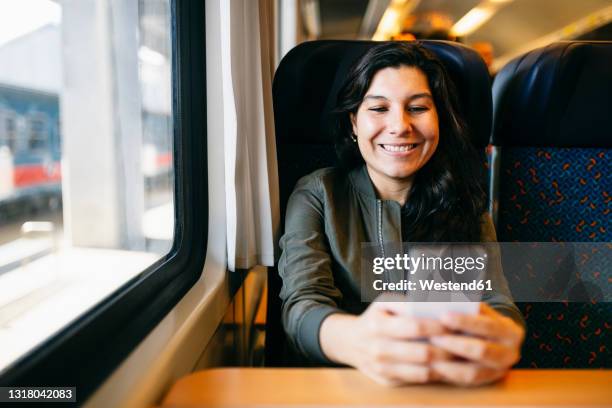 mid adult woman using mobile phone in train - train hungary stock pictures, royalty-free photos & images