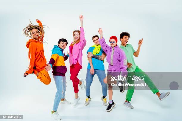 smiling young male and female friends dancing against white background - physical position fotografías e imágenes de stock