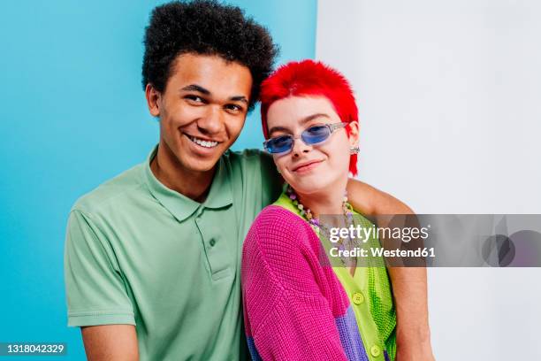 smiling redhead woman with hand on shoulder of male friend on blue and white background - man expressive background glasses stock pictures, royalty-free photos & images