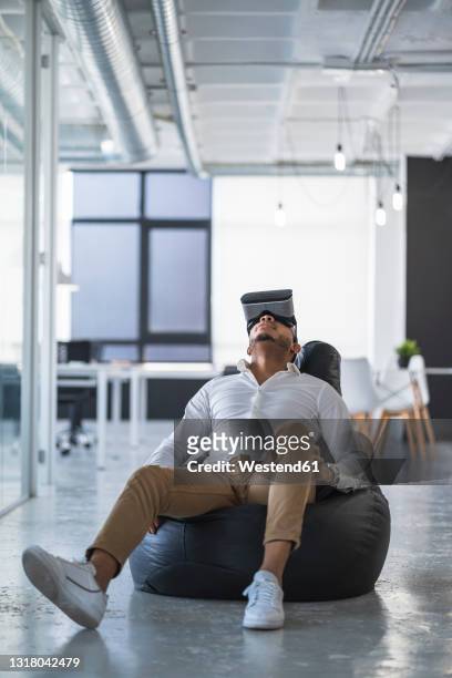 businessman using virtual reality simulator on bean bag at coworking office - bean bags fotografías e imágenes de stock