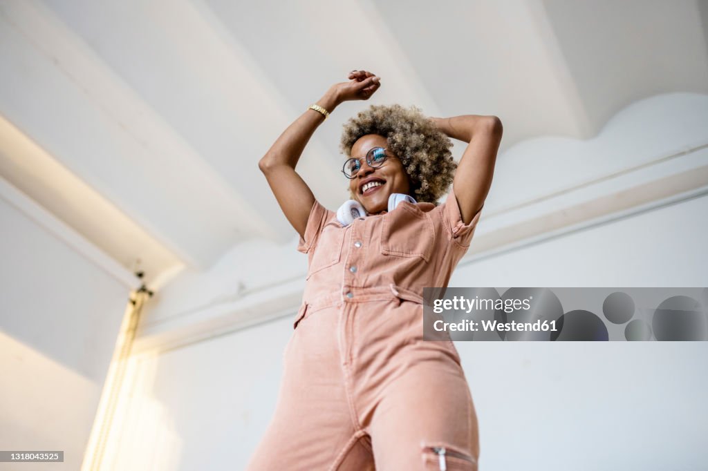 Businesswoman dancing with arms raised at home office