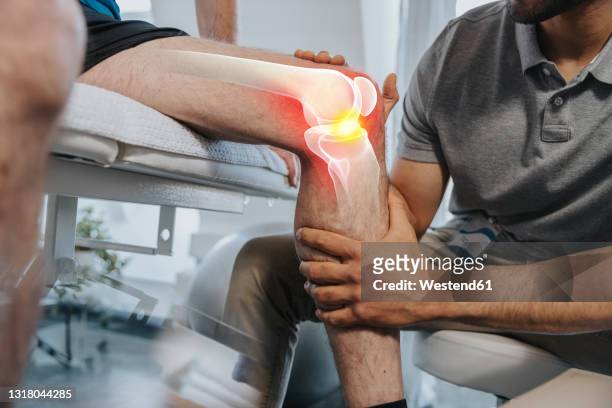 physical therapist checking knee joint of patient at medical examination room - arthritis stock-fotos und bilder