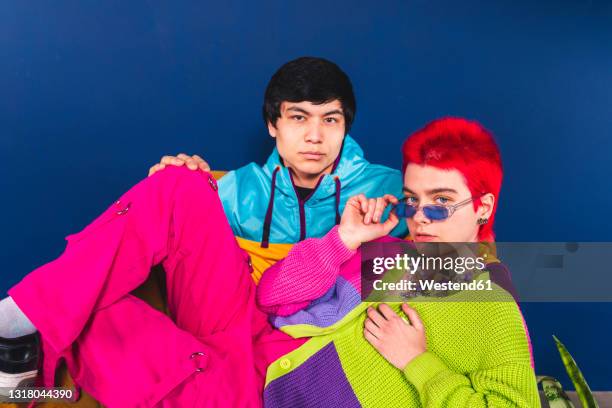 male and female friends sitting in front of blue background - straight hair bildbanksfoton och bilder