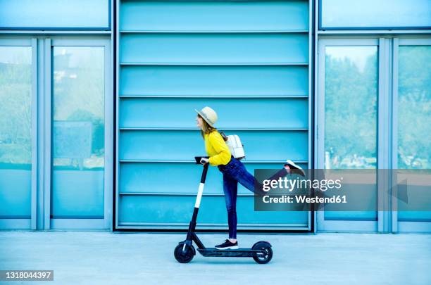 young woman enjoying electric scooter ride on footpath - push scooter stock pictures, royalty-free photos & images