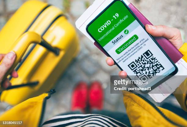woman using digital vaccine passport app оn mobile phone for traveling - yellow suitcase stock pictures, royalty-free photos & images