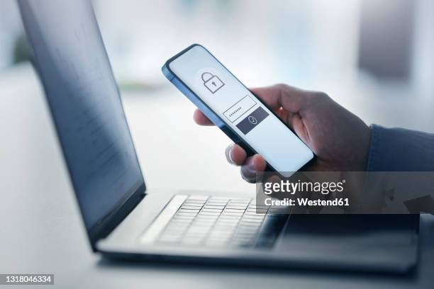 man holding smart phone with data security on display at office - beveiliging stockfoto's en -beelden