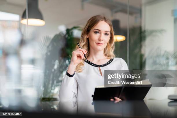female professional with diary and pen sitting at desk in office - personal organizer stock-fotos und bilder