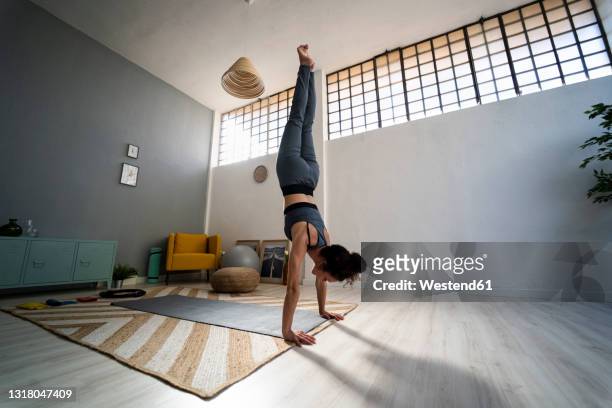 young woman balancing on hands in living room - handstand - fotografias e filmes do acervo