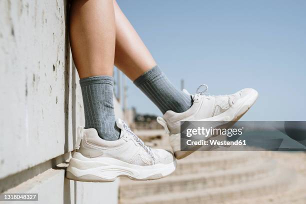 mid adult woman dangling feet while sitting on retaining wall - legs in stockings stock pictures, royalty-free photos & images