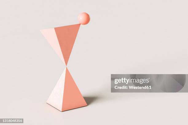 pink abstract pyramids with a sphere balancing on top against cream colored background - top angle stock illustrations
