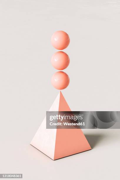 pink abstract pyramid with three spheres balancing on top against cream colored background - pyramide geometrische form stock-grafiken, -clipart, -cartoons und -symbole