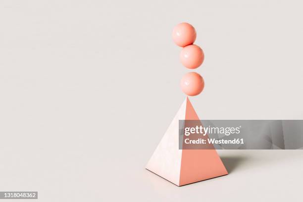pink abstract pyramid with three spheres balancing on top over cream colored background - top angle stock illustrations