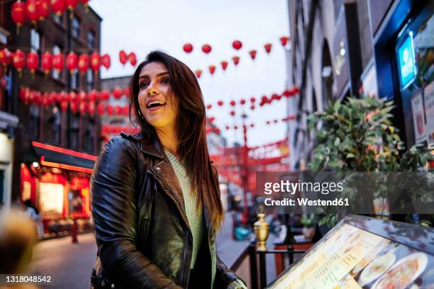 happy young woman looking away while standing in city - soho city of westminster stock-fotos und bilder