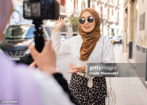 young woman with sunglasses gesturing while vlogging in city - beautiful arab girl 個照片及圖片檔