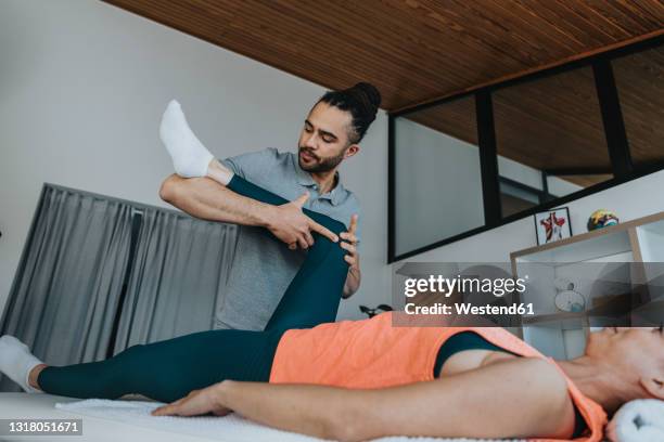 physiotherapist treating knee of female patient in medical practice - fysiotherapeut stockfoto's en -beelden