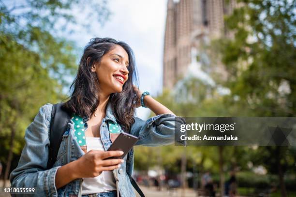 young woman enjoying sunny day of sightseeing in barcelona - indian woman phone stock pictures, royalty-free photos & images