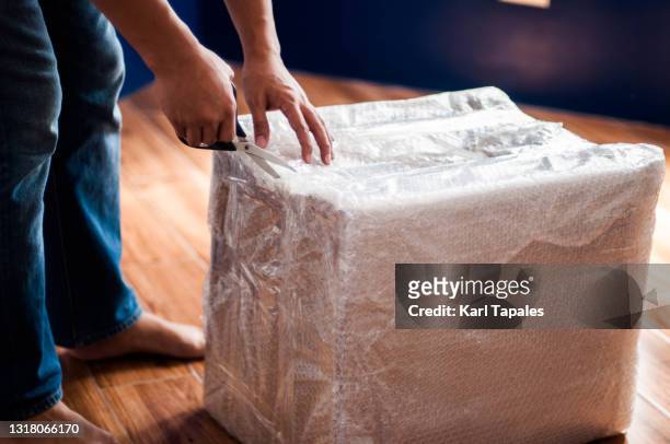a southeast asian man is opening a carton box package delivery at home - online shopping opening package stockfoto's en -beelden