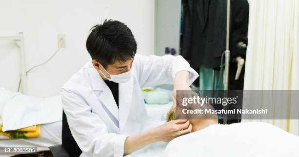 young asian male doctor gives young asian male beauty acupuncture treatment - acupuncture needle stock pictures, royalty-free photos & images