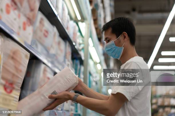 young asian man chooses diapers in the shopping mall - shenzhen mall stock pictures, royalty-free photos & images
