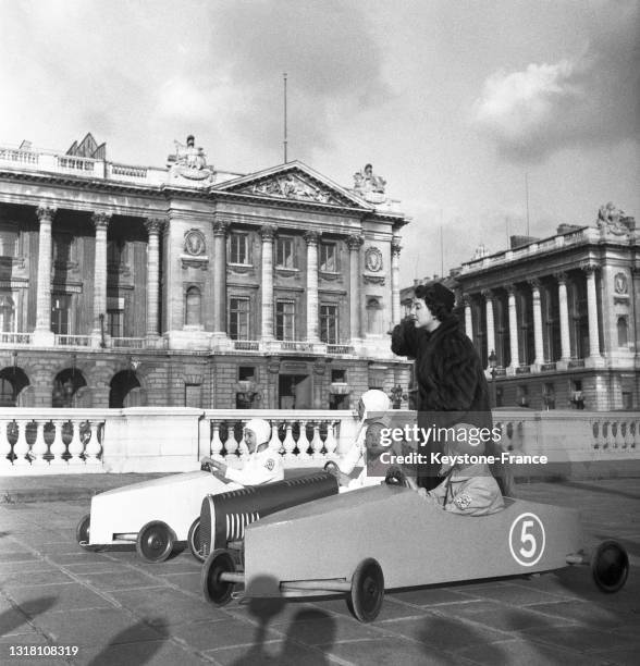 Marthe Mercadier assistant au départ de la course de caisse à savon du 'Derby automobile des moins de 15 ans', le 27 octobre 1949, à Paris.