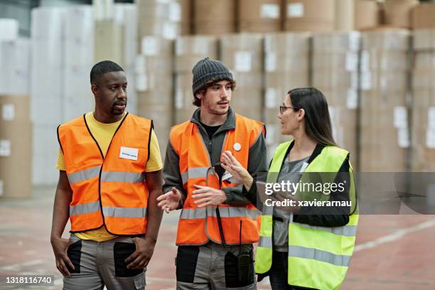 female foreperson making plans with warehousemen - safety vest stock pictures, royalty-free photos & images