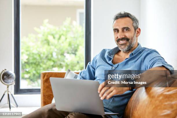 verticale de l’homme gai avec l’ordinateur portatif à la maison - un seul homme senior photos et images de collection