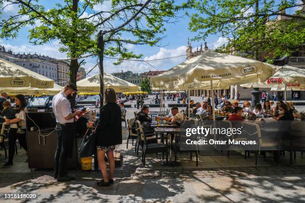 People enjoy food and drinks at an outdoor garden bar at Krakow's UNESCO listed Main Square on May 15, 2021 in Krakow, Poland. Bars and restaurants...