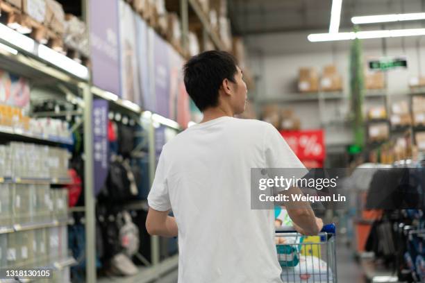 asian man pushing a trolley in a shopping mall - shopping trolley photos et images de collection