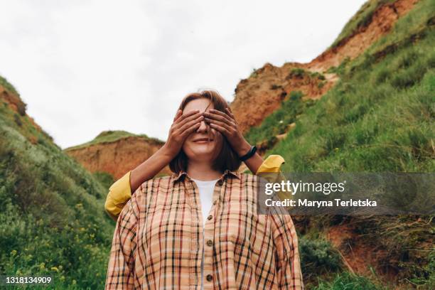 the daughter covered her mother's eyes with her hands. - milestone stock-fotos und bilder