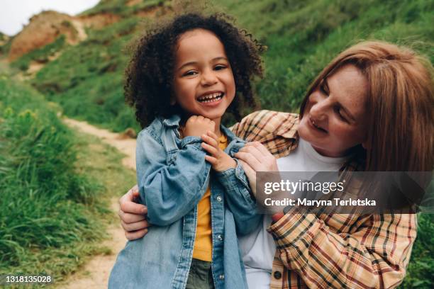 a white-skinned mother with a dark-skinned daughter is having fun. - babysitters club stock pictures, royalty-free photos & images