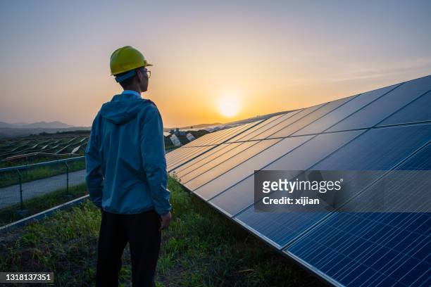 ingeniero de pie en la central solar mirando al amanecer - central eléctrica solar fotografías e imágenes de stock