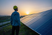 Engineer standing in solar power station looking sunrise