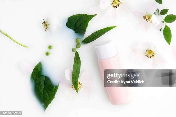 beautiful white rose flowers and cleansing milk in a pink vial in milk bath. - white rose flower spa stock-fotos und bilder