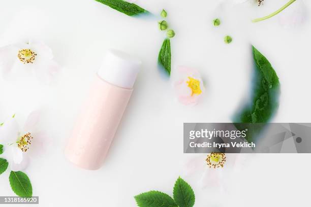 beautiful white rose flowers and cleansing milk in a pink vial in milk bath. - white rose flower spa stock-fotos und bilder