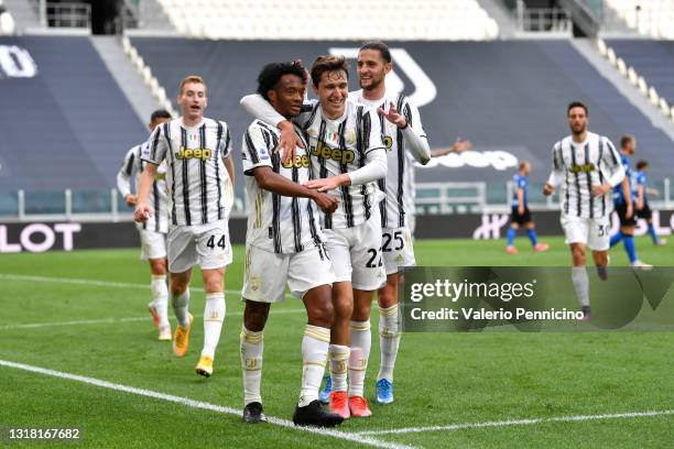 Juan Cuadrado of Juventus celebrates with team mate Federico Chiesa and Adrien Rabiot after scoring their side's second goal during the Serie A match...