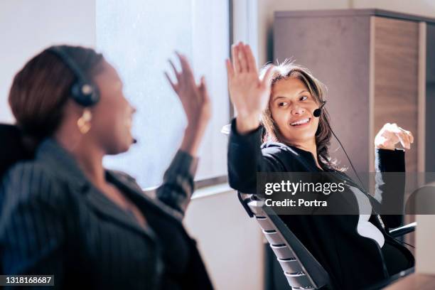 female customer support executives giving each other a high five - call center team stock pictures, royalty-free photos & images