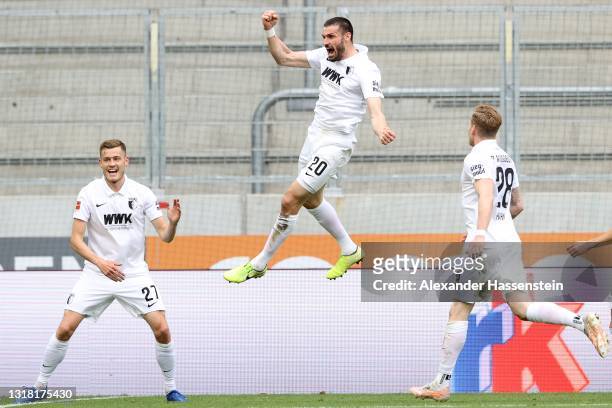 Daniel Caligiuri of FC Augsburg celebrates with Alfred Finnbogason and team mates after scoring their side's second goal from the penalty spot during...