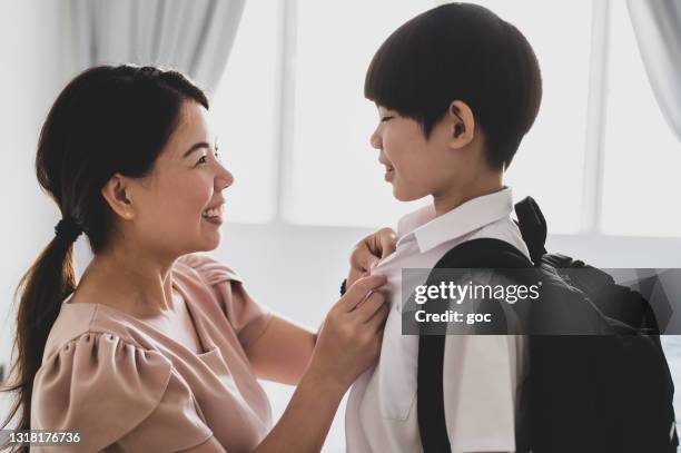 young asian mother getting ready her son in the bedroom and prepared him for school reopen day. - malaysia school stock pictures, royalty-free photos & images