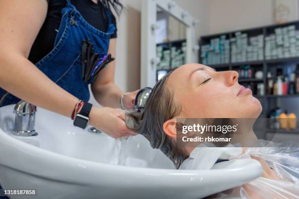 hands of hairdresser washing customer hair at salon after coloring hair dye - hornhaut stock-fotos und bilder