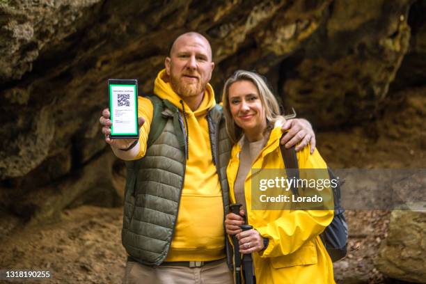 zwei wanderer zeigen ihre digitalen impfpässe - impfpass reisedokument stock-fotos und bilder