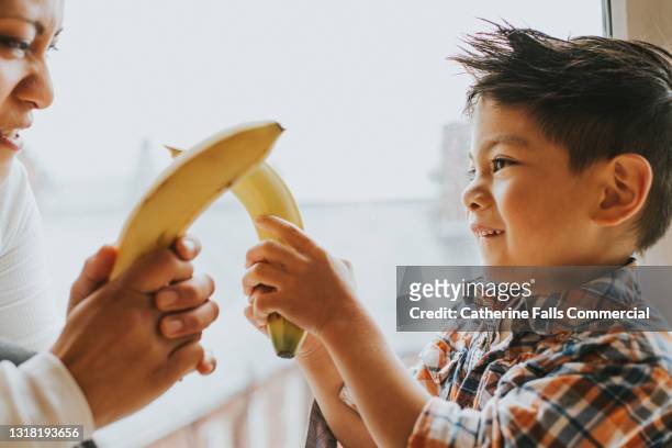 mother and son have a playful banana sword fight - sword fight stock pictures, royalty-free photos & images