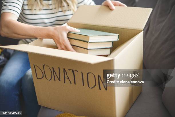 woman puts donations in a box - donation box stock pictures, royalty-free photos & images