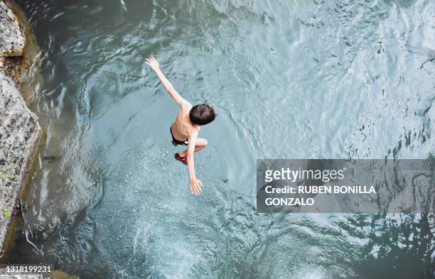 aerial view of a caucasian young boy jumping from rock into river or lake - river aerial stock pictures, royalty-free photos & images