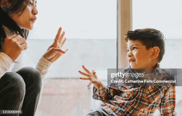 a little boy uses sign language to talk to a woman - dove stockfoto's en -beelden