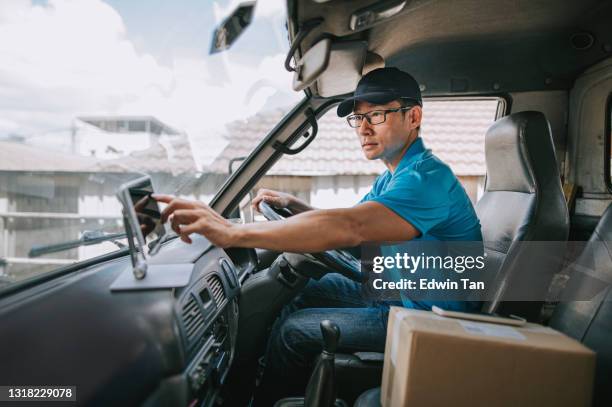 aziatische chinese rijpe mannelijke leveringspersoon die digitale tablet mobiele app gebruikt die leveringsinformatie in bestuurderszetel in bestelwagen controleert - courier stockfoto's en -beelden